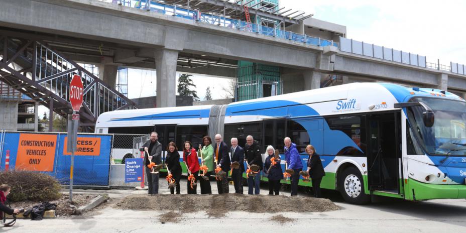 Groundbreaking ceremony in front of transit bus.-