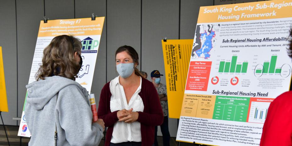 Two people talking next to presentation board.