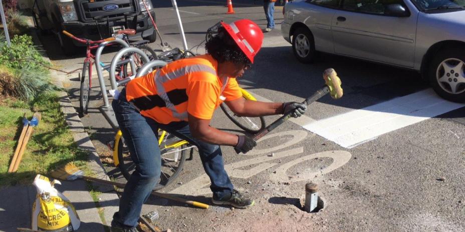 Female SDOT employee hammers survey marker into asphalt.