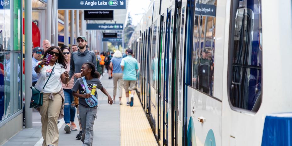 At the train station, two riders walk towards the oncoming train.